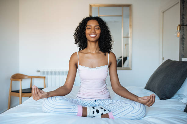 istock Attractive black woman on bed meditating 1143516621