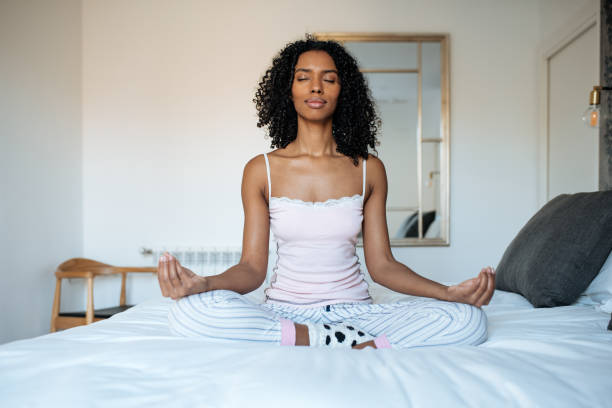 istock Attractive black woman on bed meditating 1143516626