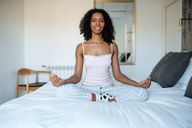 istock Attractive black woman on bed meditating 1143516657