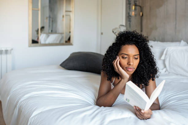 istock Woman lying down on bed reading a book 1143516692