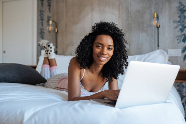 istock Woman sitting on bed on the computer 1143516717
