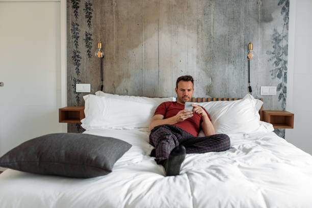 istock Man sitting on bed with mobile phone 1143516727