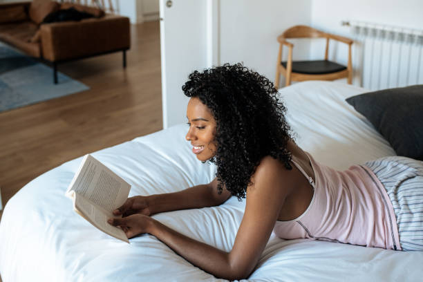 istock Woman lying down on bed reading a book 1143516732