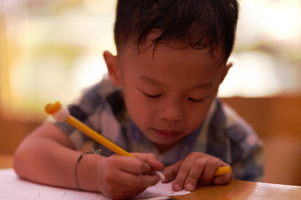 istock Boy concentrates in writing on paper homework 1143516768