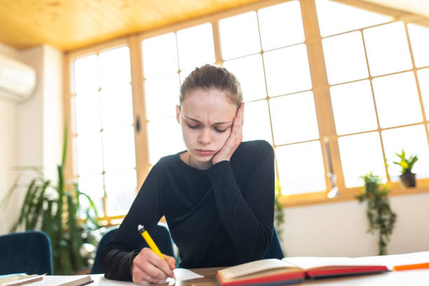 tired school girl doing homework - homework pencil people indoors imagens e fotografias de stock