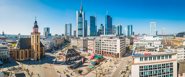 Panoramic view across the plaza of Hauptwache and stores of the Zeil shopping area overlooked by the spires of St. Catherine’s Church and the futuristic skyscrapers of Frankfurt’s central business district, Germany.