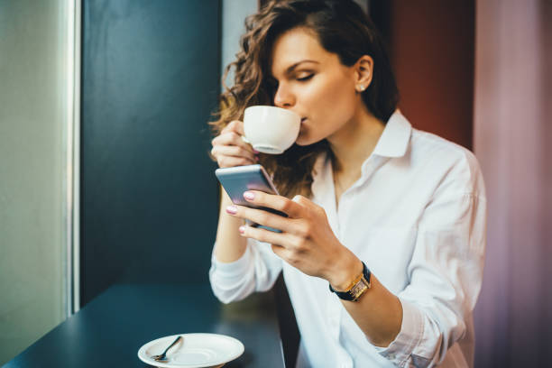istock Beautiful young woman drinking coffee and texting 1143522414