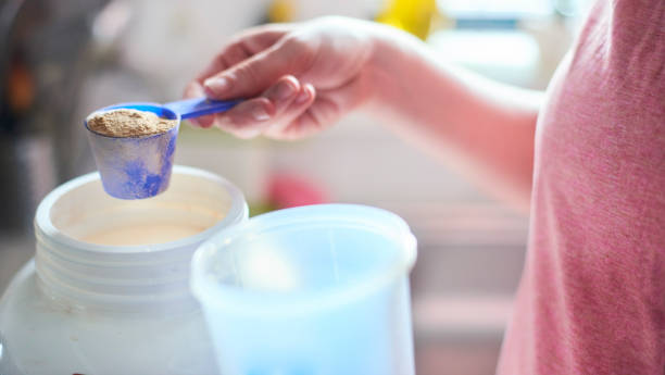 Measuring out Protein powder Measuring out protein powder with a measuring scoop from the container serving utensil stock pictures, royalty-free photos & images