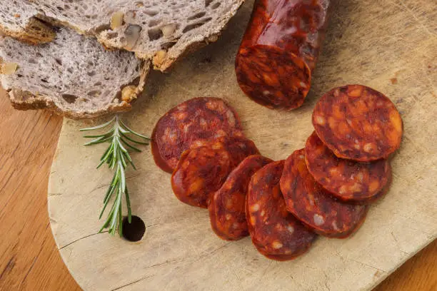 Iberian chorizo, Spanish chorizo or Spanish sausage cut into slices on a wooden board with rustic bread