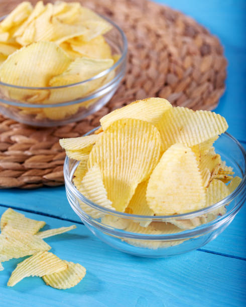 istock Potato chips and potato on wooden backround. 1143525670