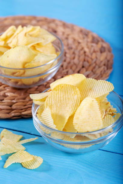 istock Potato chips and potato on wooden backround. 1143525756