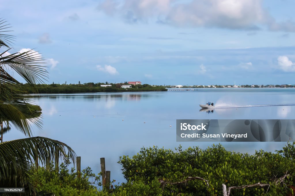 Foto de Um Bom Dia Para Pescar Nas Chaves De Floridaum Barco De Pesca  Pequeno Compete Através Da Água Em Um Oceano Como O Vidro Que Reflete Um  Céu Muito Azul Com