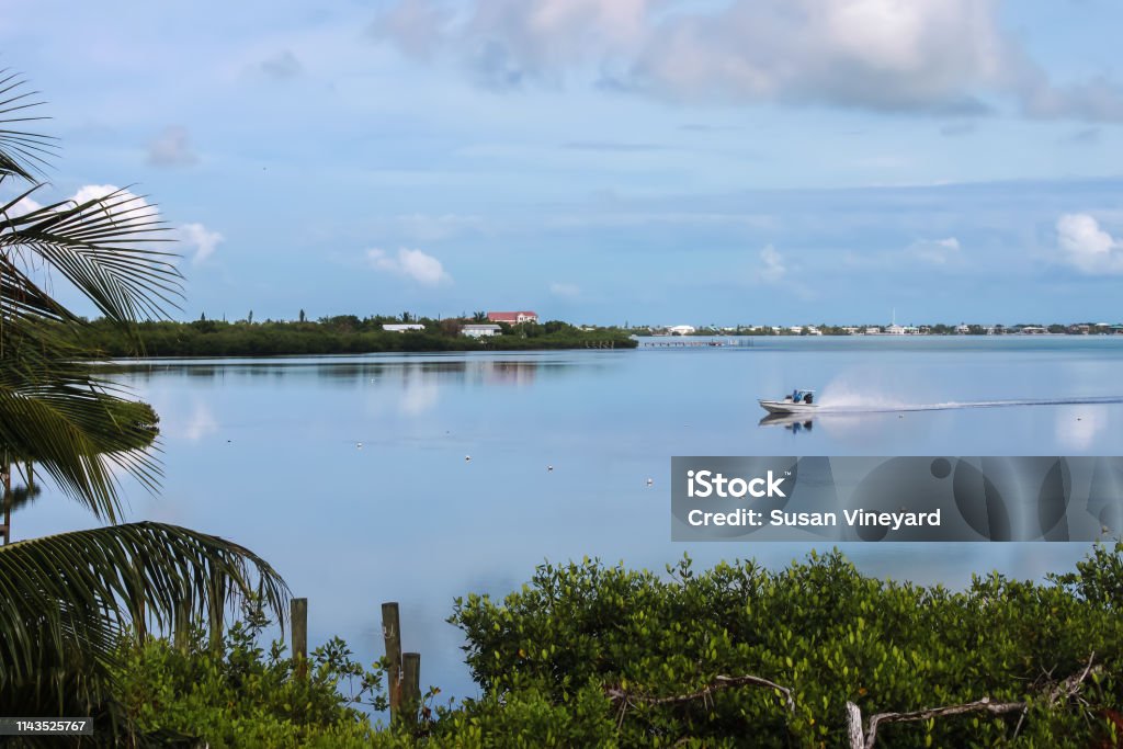 Foto de Um Bom Dia Para Pescar Nas Chaves De Floridaum Barco De Pesca Pequeno Compete Através Da Água Em Um Oceano Como O Vidro Que Reflete Um Céu Muito Azul Com Foto de Um Bom Dia Para Pescar Nas Chaves De Floridaum Barco De Pesca Pequeno Compete Através Da Água Em Um Oceano Como O Vidro Que Reflete Um Céu Muito Azul Com