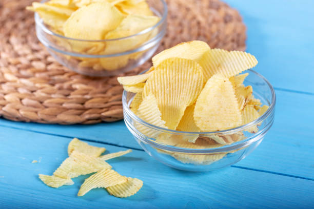 istock Potato chips and potato on wooden backround. 1143526540