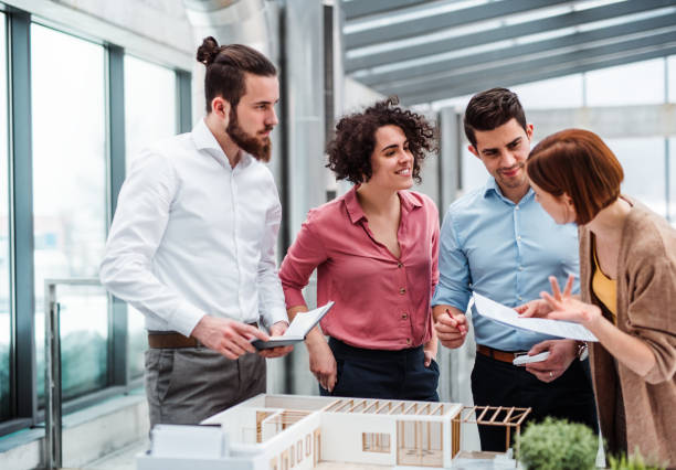 istock Group of young architects with model of a house working in office, talking. 1143526594
