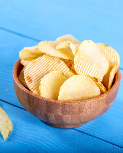 istock Potato chips and potato on wooden backround. 1143526945