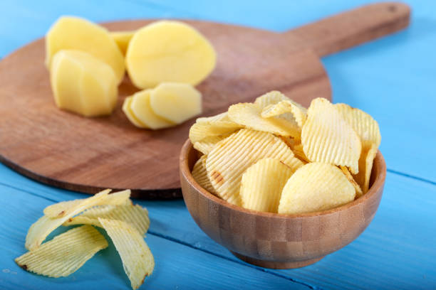 istock Potato chips and potato on wooden backround. 1143527271