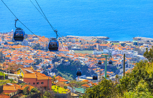 Aerial view of traditional overhead cable cars transporting tourists above Funchal city in Madeira island of Portugal