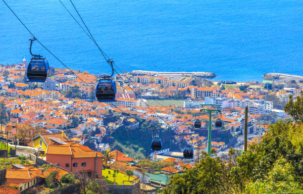 Cable cars above Funchal capital in Madeira Aerial view of traditional overhead cable cars transporting tourists above Funchal city in Madeira island of Portugal overhead cable car photos stock pictures, royalty-free photos & images