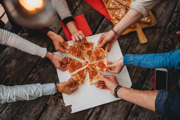 amigos tomando una porción de pizza de la caja de pizza - pizza party fotografías e imágenes de stock