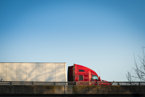 Tractor trailer trucking big rig on highway overpass with blue sky and copy space