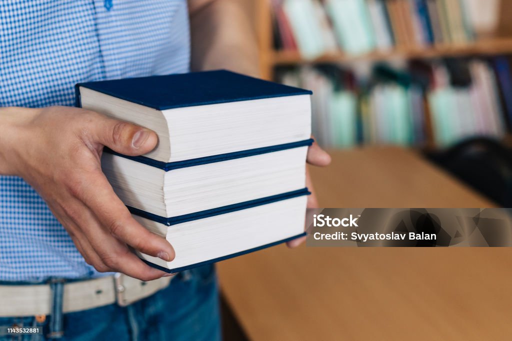 Male hands holding a stack of books. Advice Stock Photo