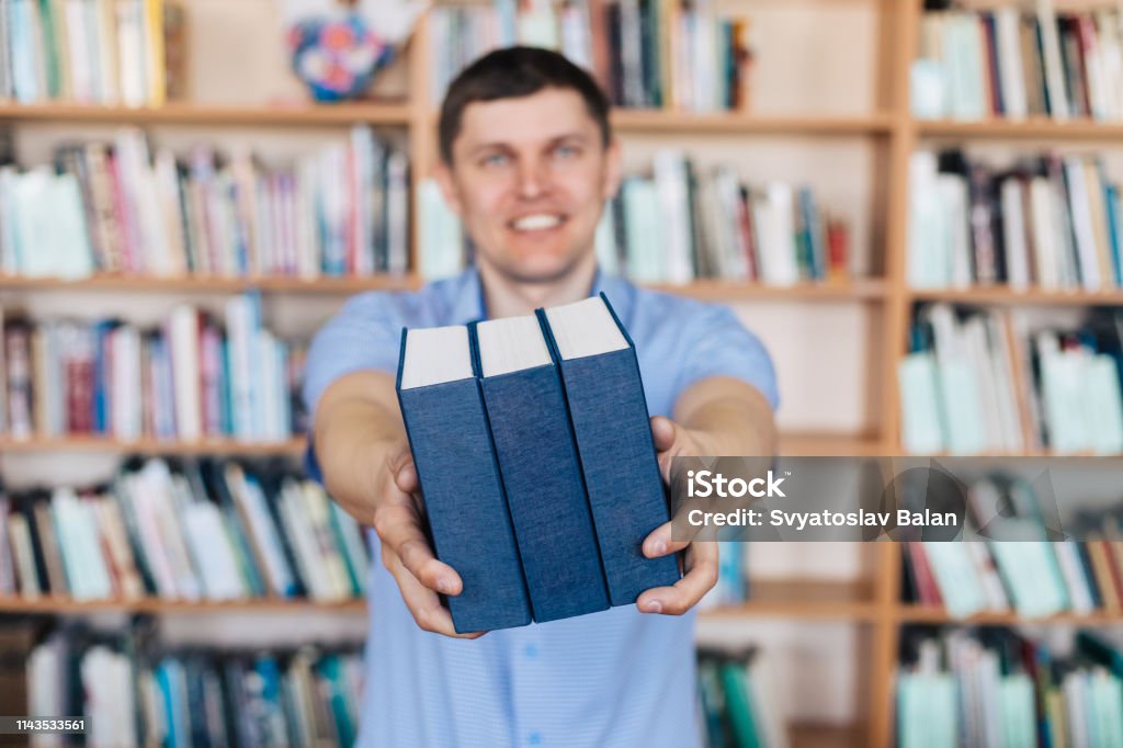 Manos masculinas sosteniendo una pila de libros. El hombre sostiene una pila de libros - Foto de stock de Agarrar libre de derechos