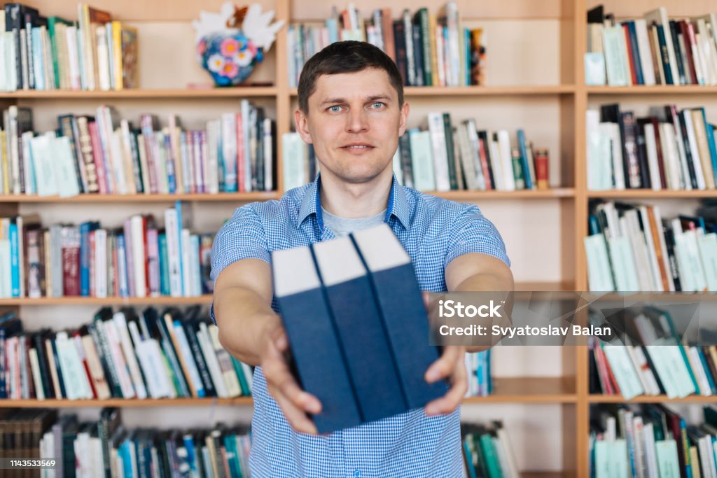 Male hands holding a stack of books. Man holds out a stack of books Advice Stock Photo