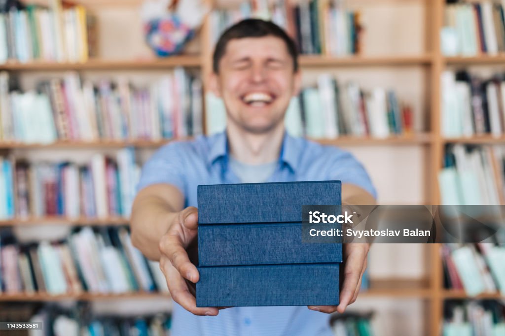 Male hands holding a stack of books. Man holds out a stack of books Advice Stock Photo