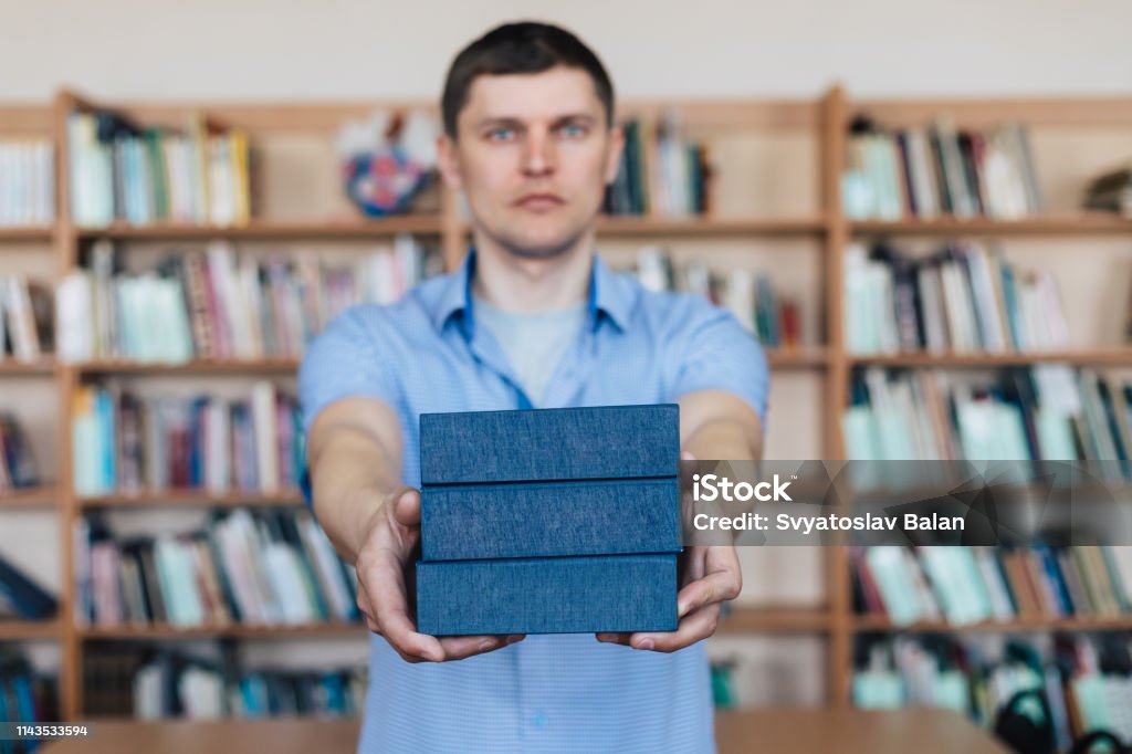 Male hands holding a stack of books. Man holds out a stack of books Advice Stock Photo