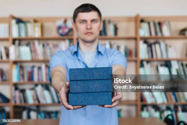 Male Hands Holding A Stack Of Books Man Holds Out A Stack Of Books Stock Photo - Download Image Now