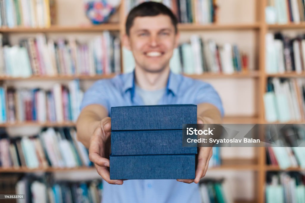 Male hands holding a stack of books. Man holds out a stack of books Advice Stock Photo