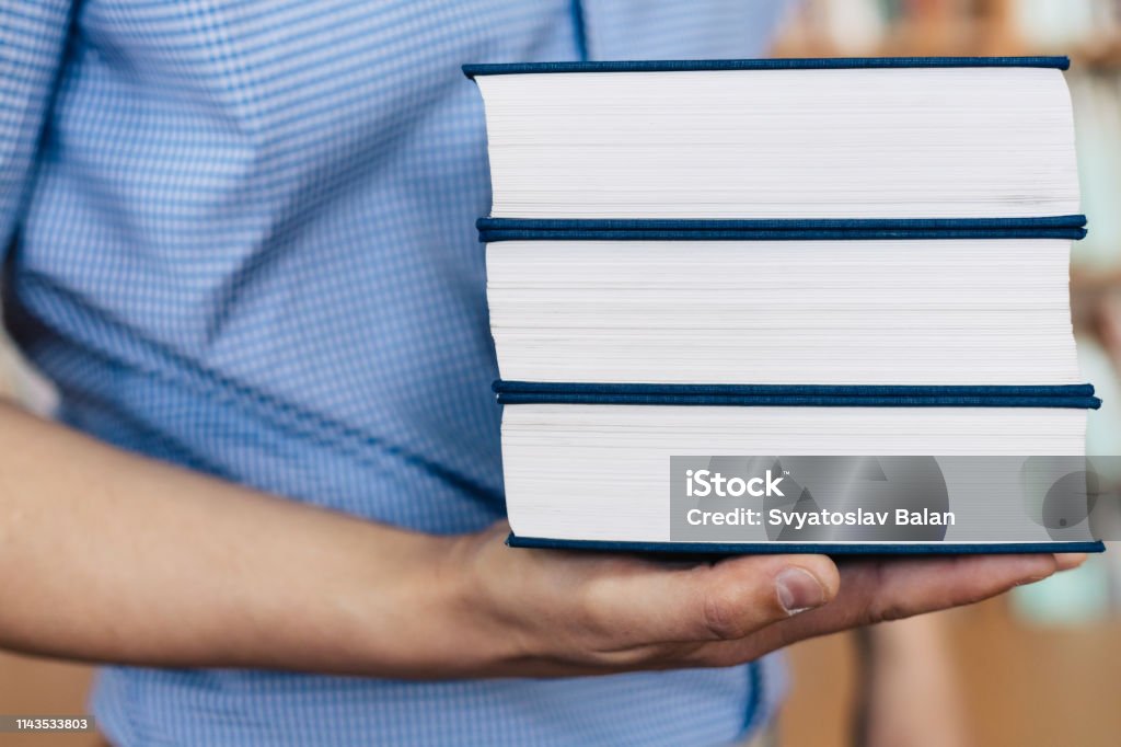 Pila de libros tumbados en la palma - Foto de stock de Agarrar libre de derechos