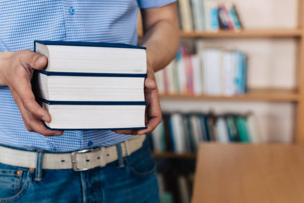 istock Male hands holding a stack of books. 1143533831