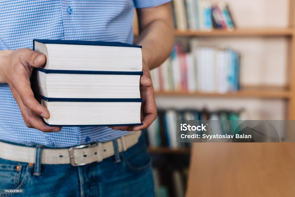 Male hands holding a stack of books. Advice Stock Photo
