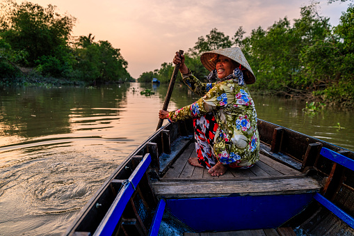 Vietnamese woman rowing a boat, Mekong River Delta, Vietnam