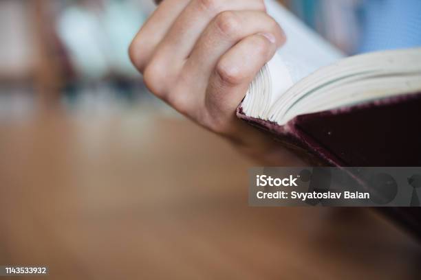 Male Hand Holds The Opened Book View Of The Book Back Closeup Stock Photo - Download Image Now