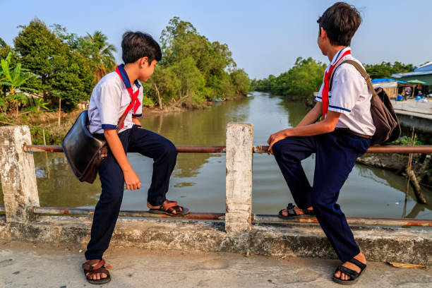 istock Two Vietnamese schoolboys sitting on a bridge, Mekong River Delta, Vietnam 1143533934