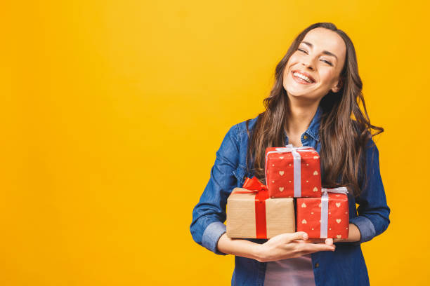 istock Young smiling model hold gift box. Woman isolated on yellow background. 1143535071