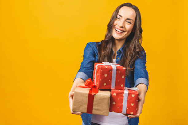 istock Young smiling model hold gift box. Woman isolated on yellow background. 1143535240