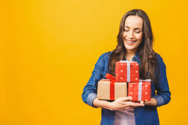 istock Young smiling model hold gift box. Woman isolated on yellow background. 1143535251