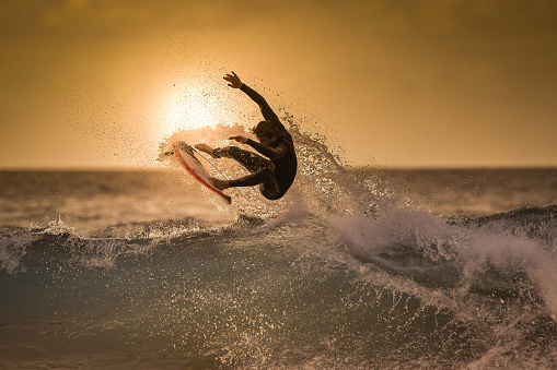 Shot of a Caucasian woman walking on the beach with surfboard over her head