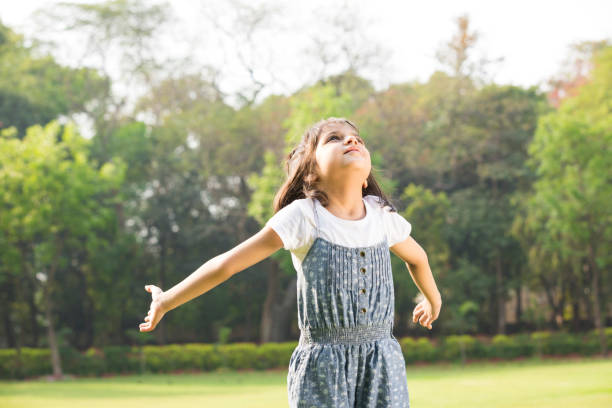 istock Girl with arms outstretched at park - Stock image 1143541663