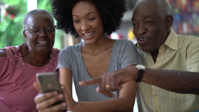 Woman showing cellphone to senior couple, people smiling and having fun