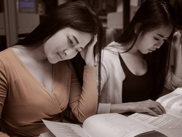 istock Two Female student reading a book for the exam or doing homework.young asian college student at hard exam. 1143545150