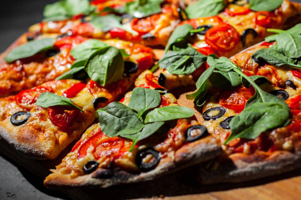 istock Pizza with Mozzarella cheese, Tomatoes, pepper, olive, Spices and Fresh spinach. Italian pizza. Pizza Margherita or Margarita on Dark grey black slate background 1143550692