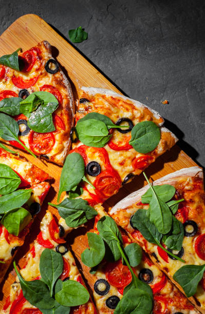 istock Pizza with Mozzarella cheese, Tomatoes, pepper, olive, Spices and Fresh spinach. Italian pizza. Pizza Margherita or Margarita on Dark grey black slate background 1143550755