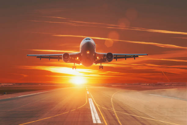 istock Commercial jet airplane flying over runway dramatic sunset sky. 1143550931