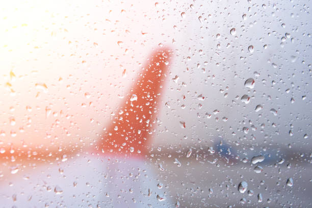 scende sulla finestra di vetro dell'aereo a fuoco, l'ala è sfocata. - runway airport sky wet foto e immagini stock