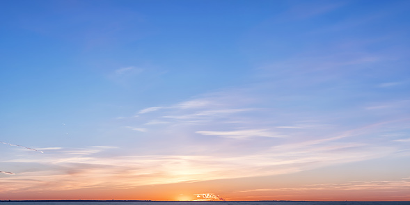 Winter horizon at sunset. Bright colored clouds and sky over setting sun with distant smoke